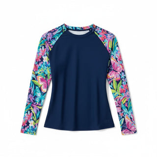A women's pretty floral print rash guard long-sleeve swim top with a solid navy blue body and vibrant tropical floral print raglan sleeves, shown on a plain white background.